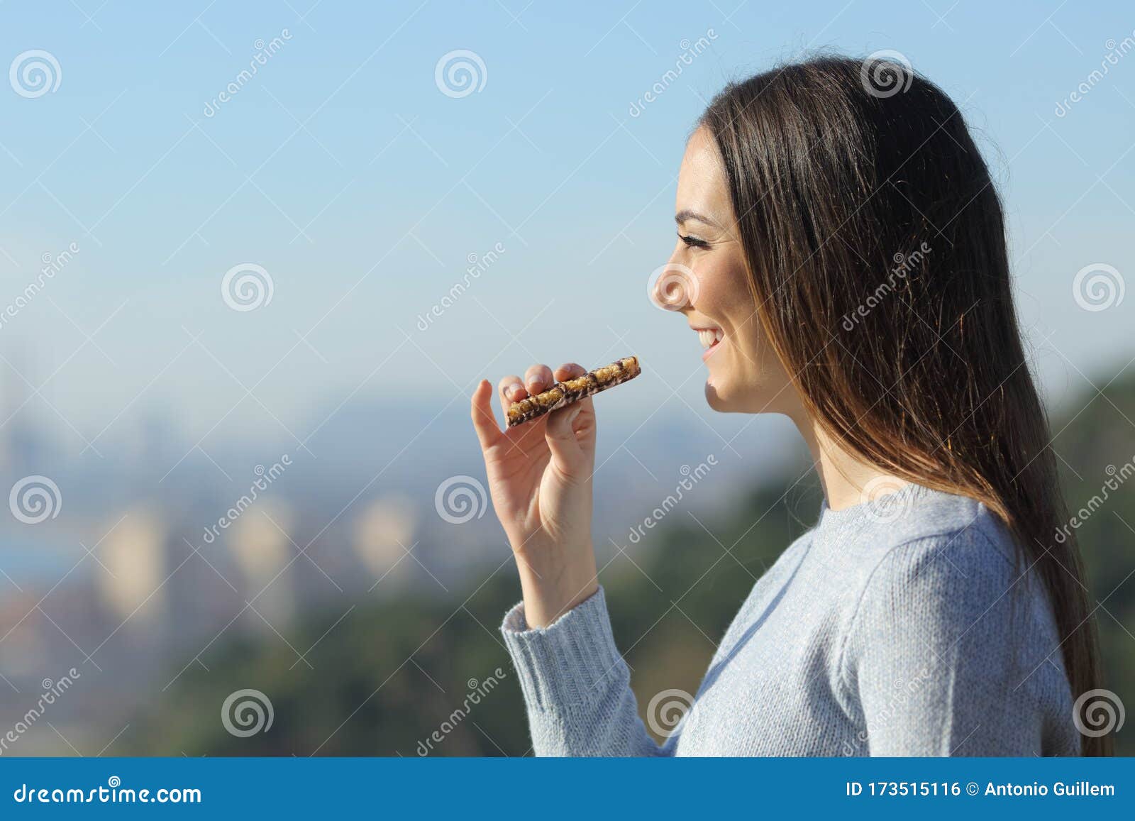 happy girl eating a snack bar in the city outskirts