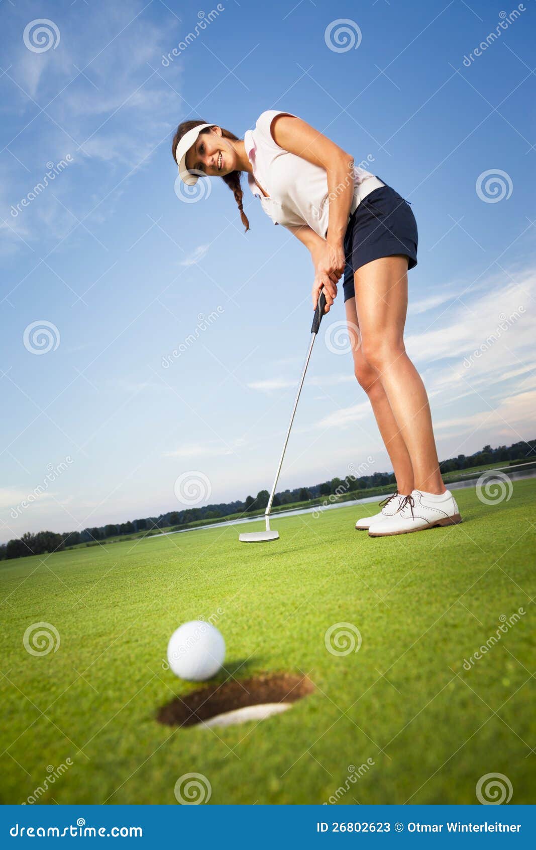 happy girl golfer putting ball into hole.