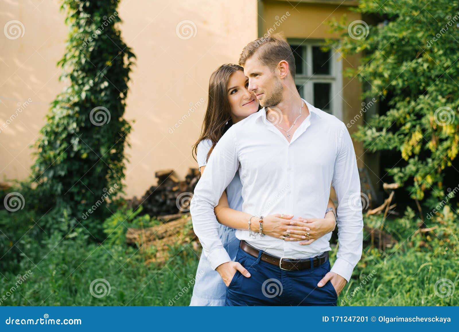 A Happy Girl Hugs Her Boyfriend from Behind and Looks at Him with