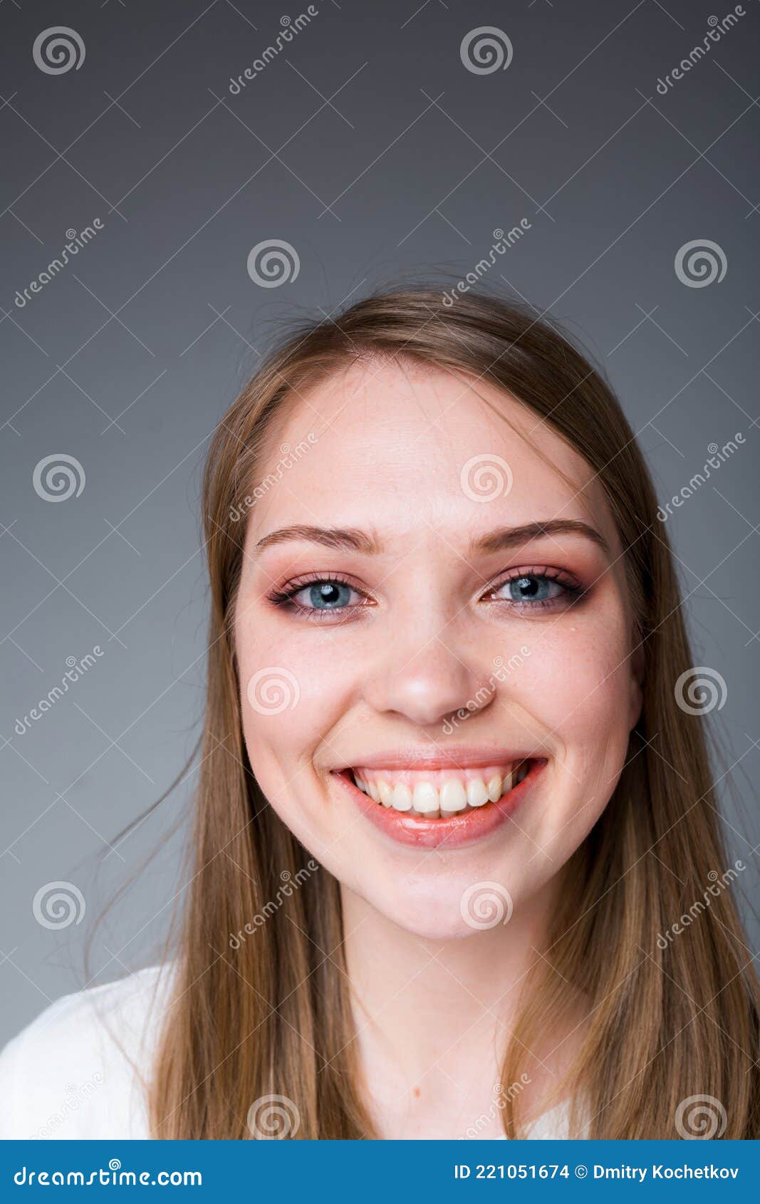 happy girl with long hair smiling broadly showing snow-white teeth and looking at the camera