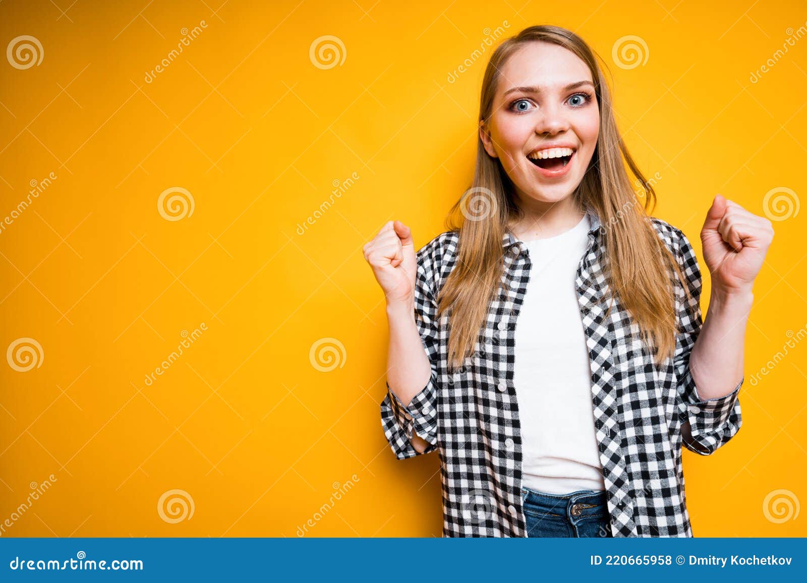 happy girl in a plaid shirt rejoices in victory clenching her hands into fists, opening her mouth