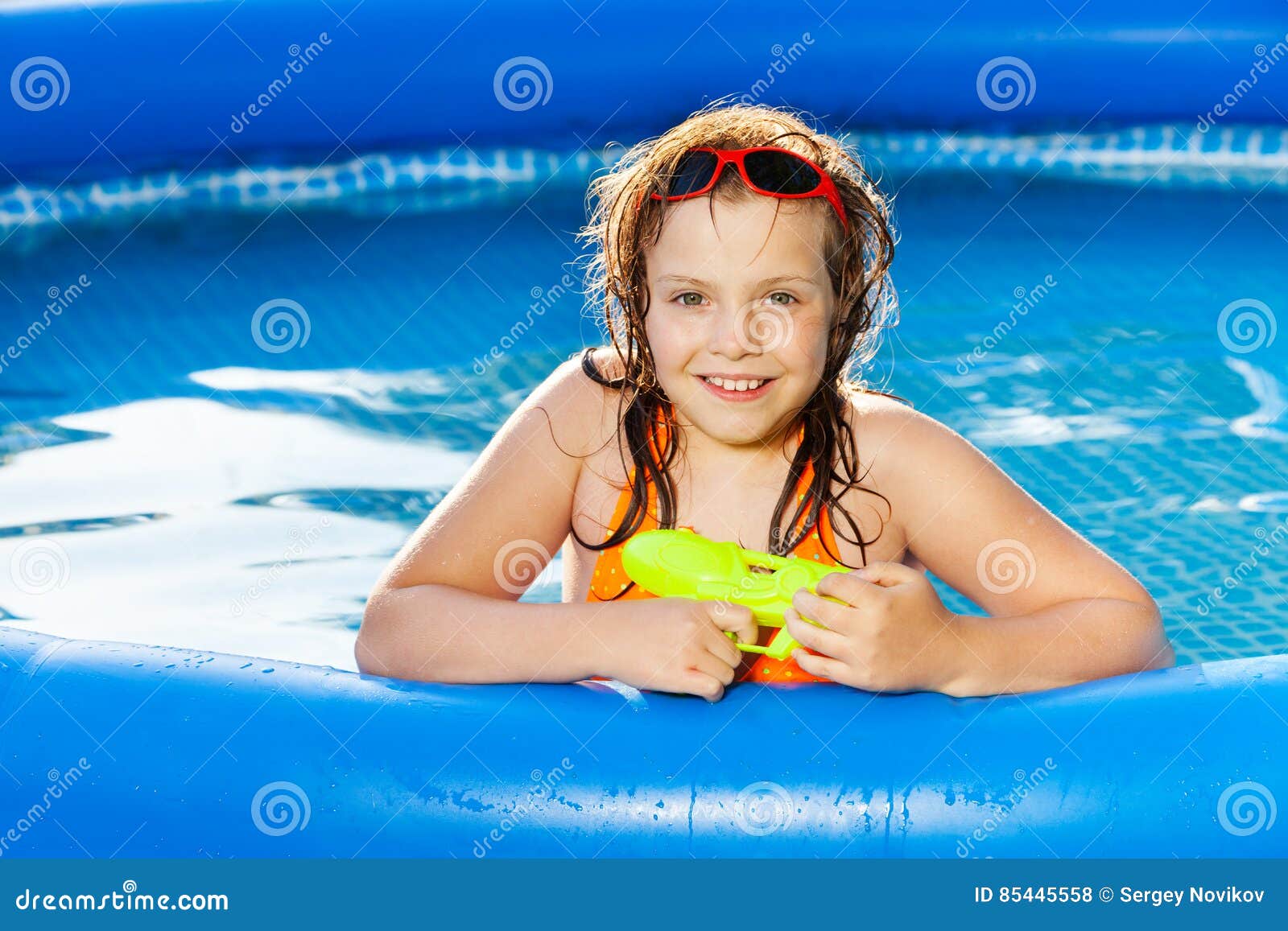 happy girl playing with water gun in the pool