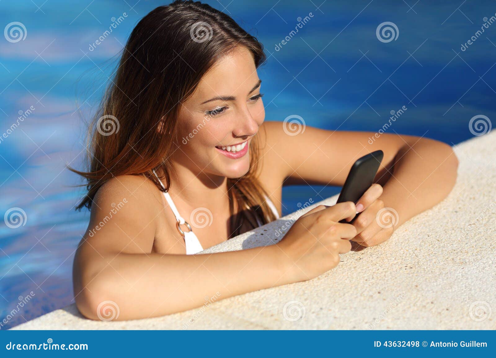 happy girl using a smart phone in a swimming pool in summer vacations