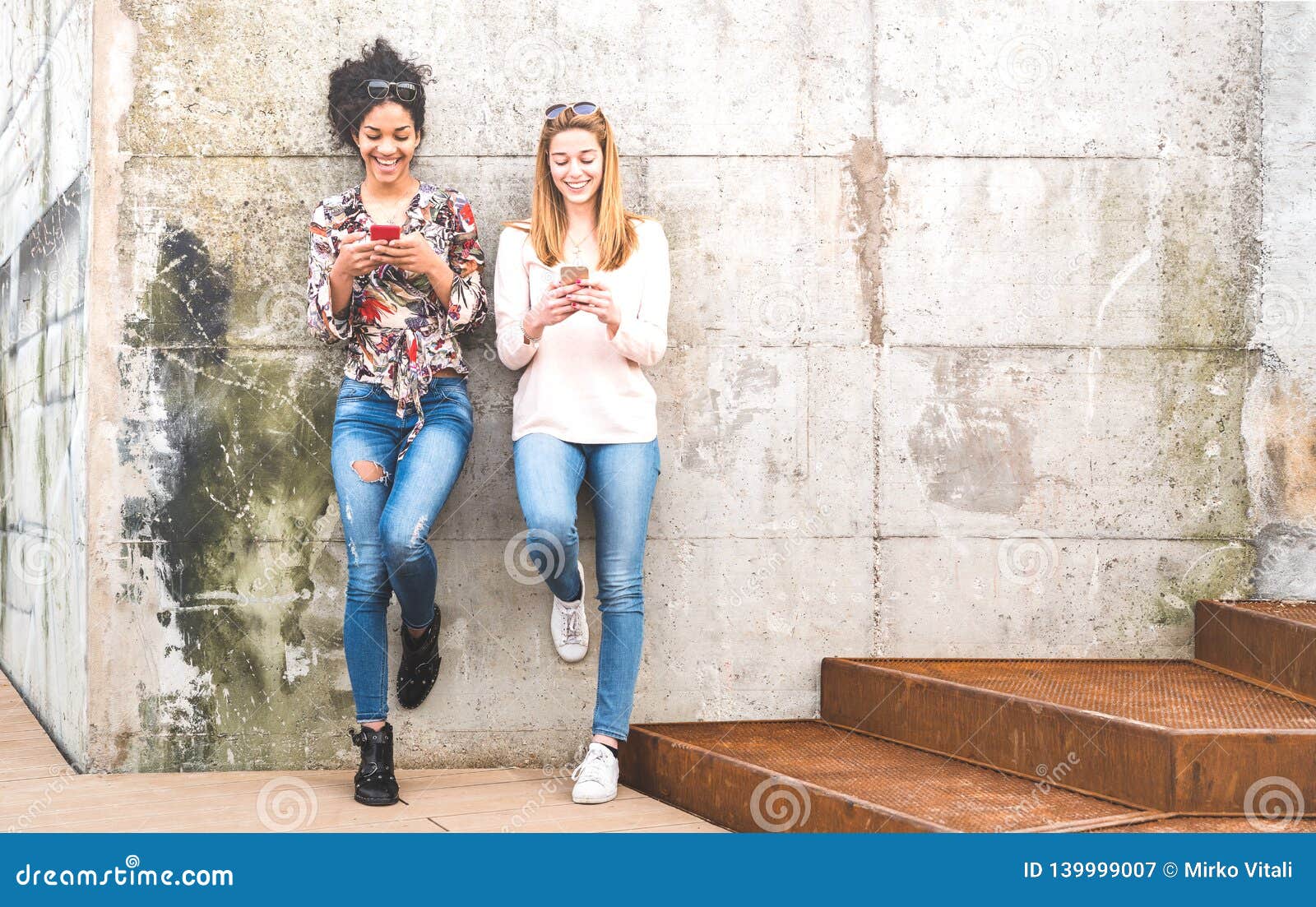 happy girls best friends having fun outdoors with mobile smart phone - friendship concept with millenial girlfriends