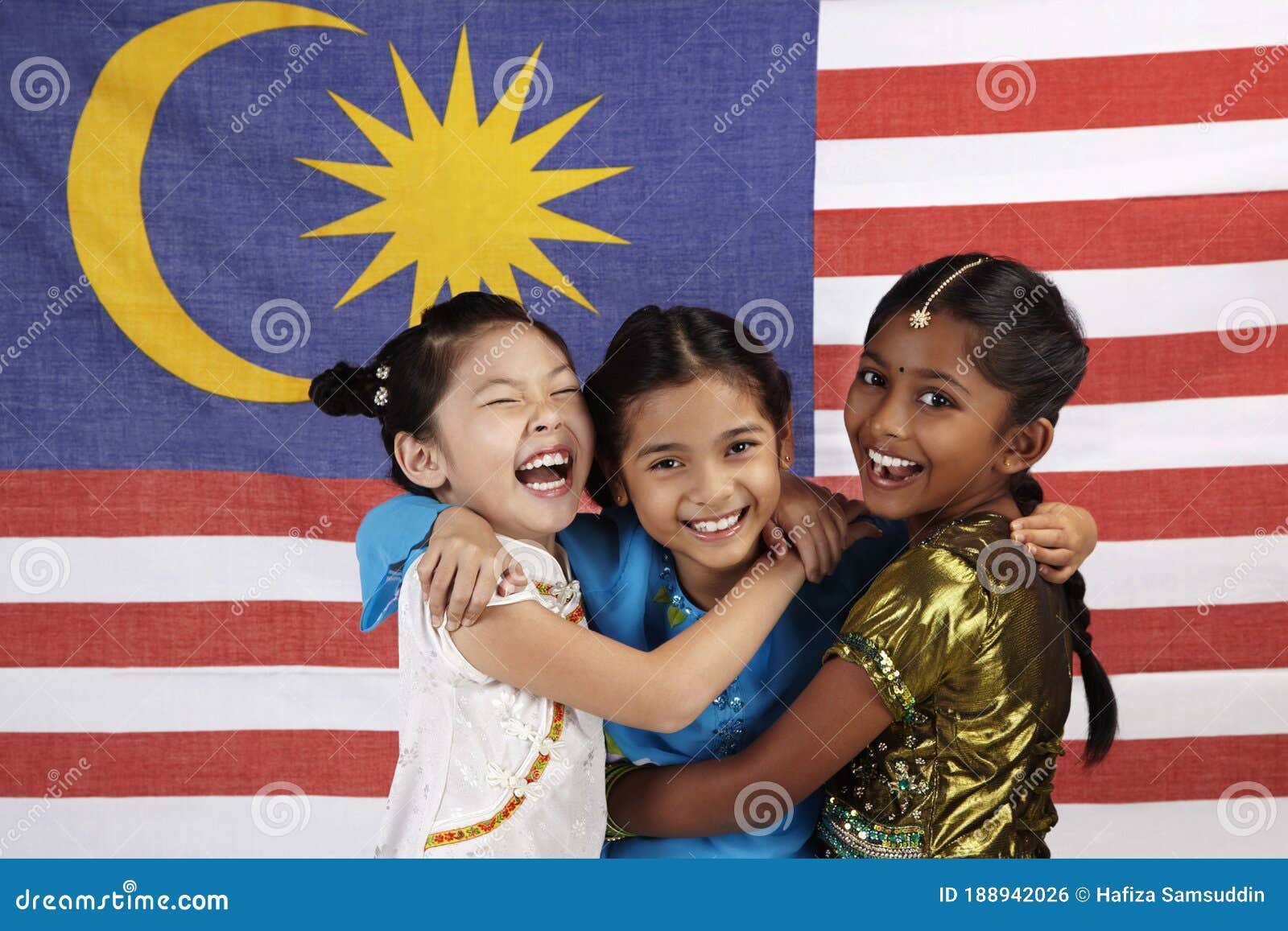 happy girls hugging each other with malaysian flag in the background. conceptual image