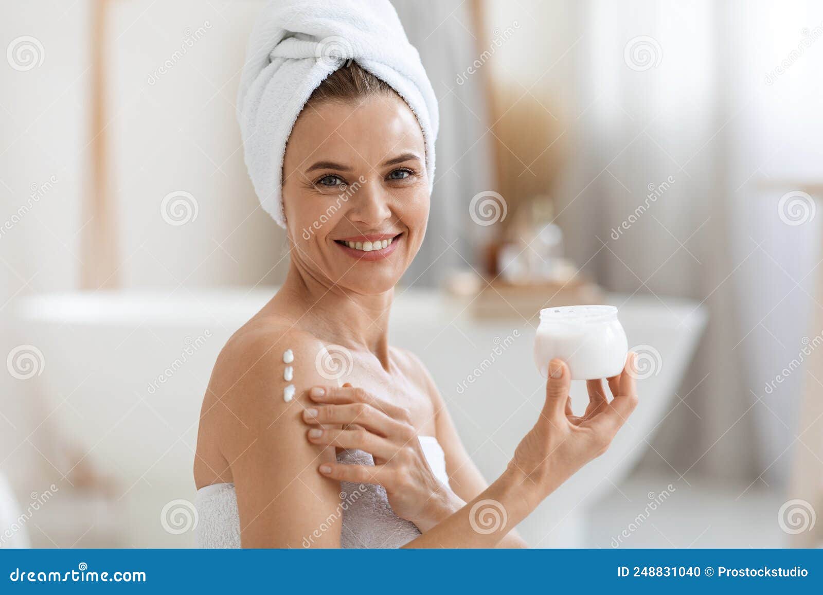 happy adult lady using body lotion after shower