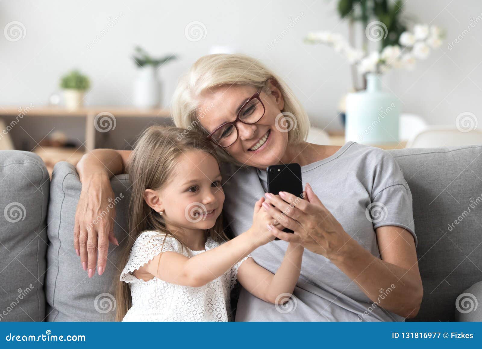 happy grandmother and cute granddaughter using cellphone making