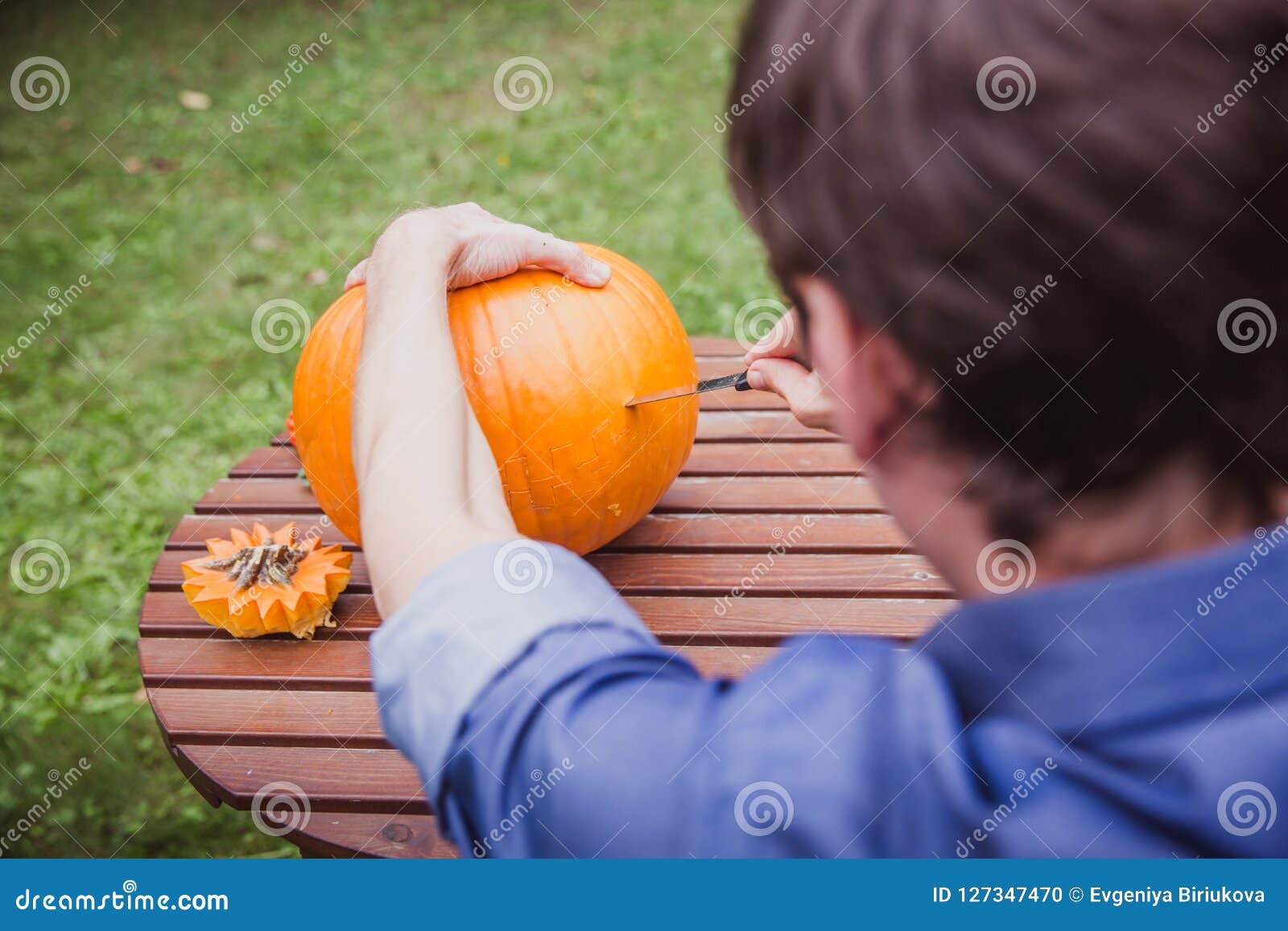 happy halloween. man carving big pumpkin jack o lanterns for halloween outside. close-up