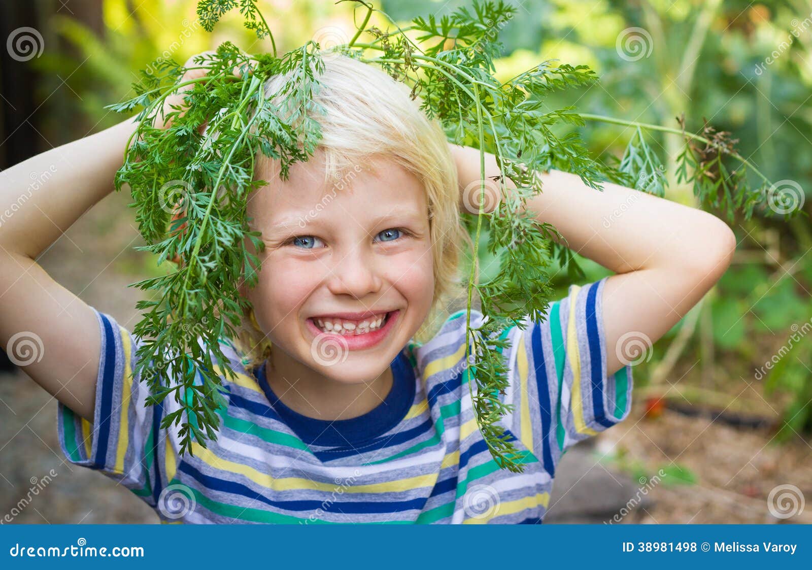 Happy Healthy Child with Carrot Top in Vegetable Garden Stock Photo