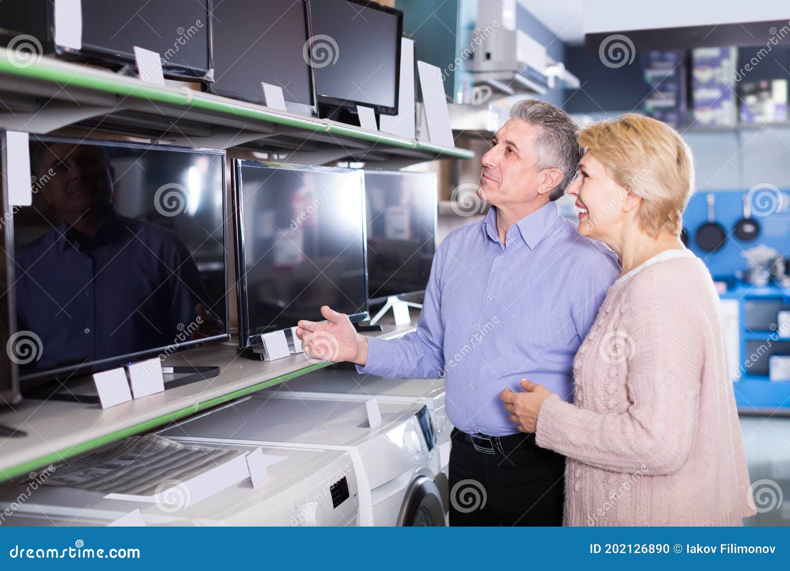 happy husband and wife choose for themselves tv in center of electronics