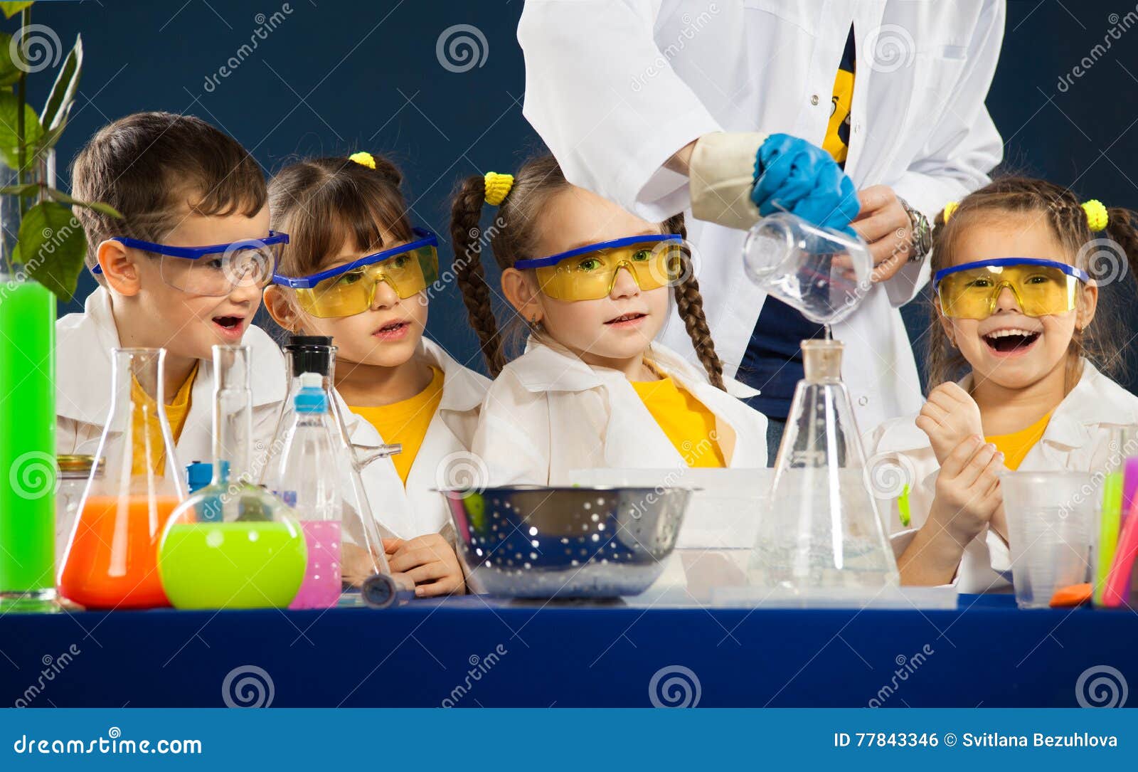 happy kids with scientist doing science experiments in the laboratory