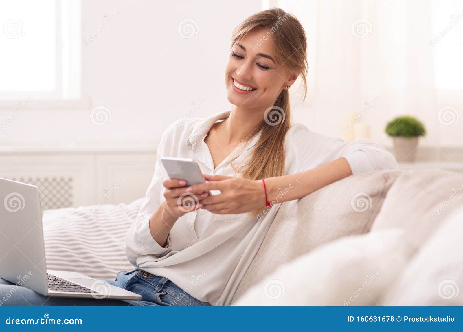 Lady Using Cellpone and Laptop Relaxing on Couch at Home Stock Photo ...
