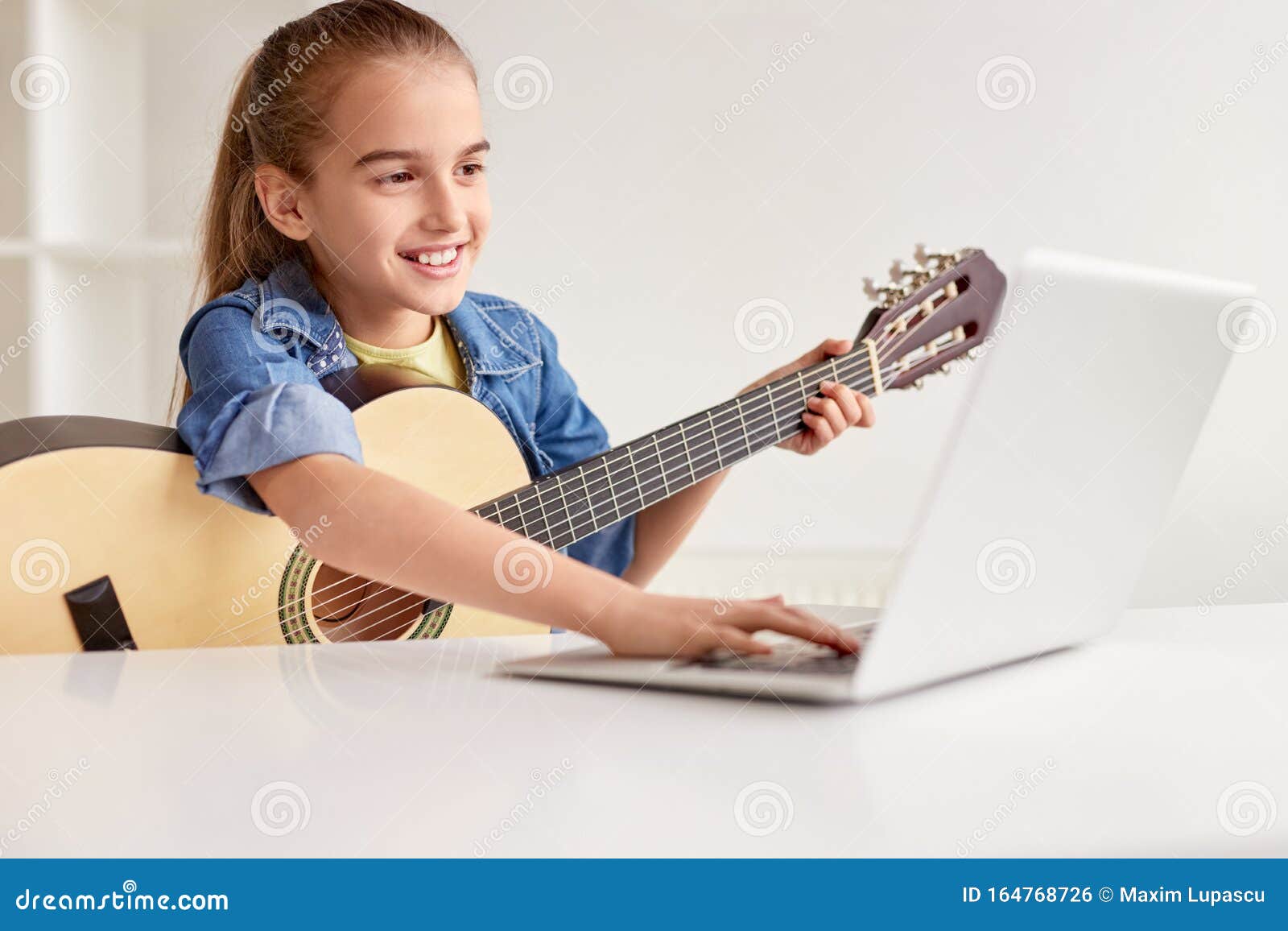 cheerful girl with guitar using laptop