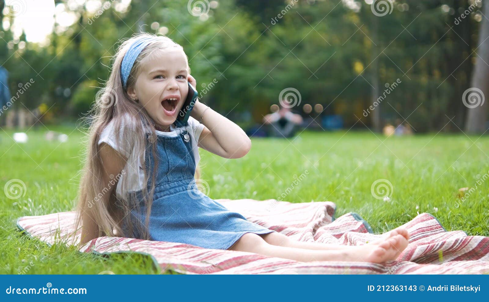 happy little child girl having conversation talking on her sellphone in summer park