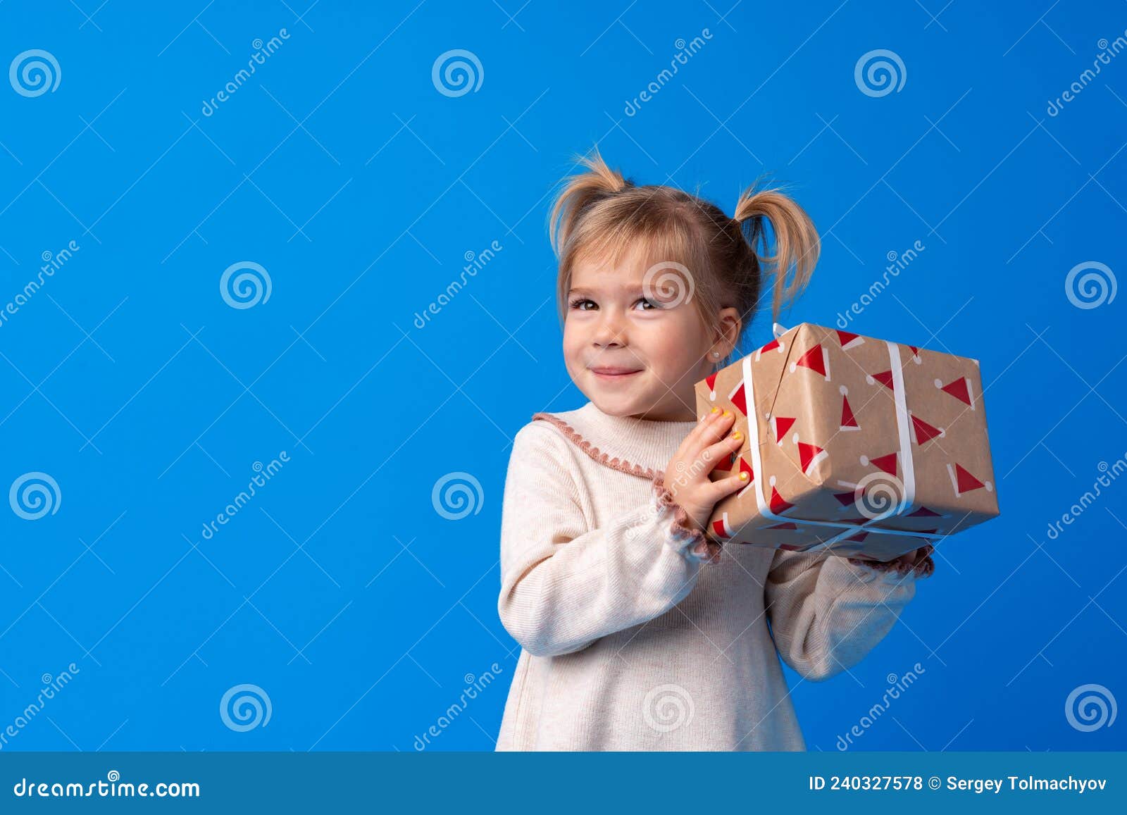 Happy Little Girl Holding Agift Box on a Blue Background Stock Photo ...