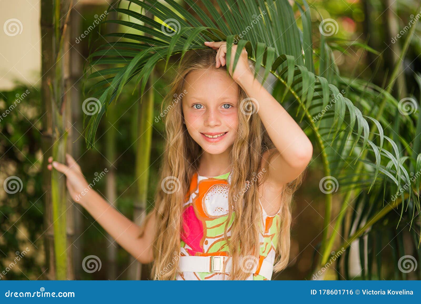 Portrait Of Smiling Cute Little Girl At Green Of Summer 