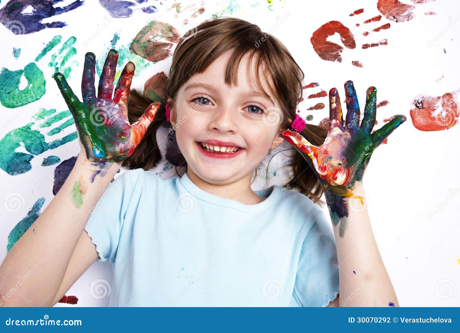 Happy little girl playing with colors on a white paper