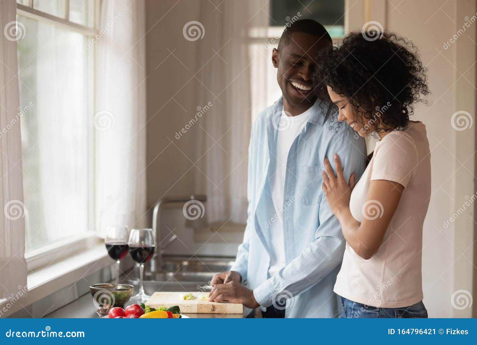 Happy biracial couple enjoy romantic date together. Happy loving african American couple enjoy weekend at home cooking in kitchen together, smiling caring biracial husband and wife have fun rest indoors prepare food spend romantic domestic date