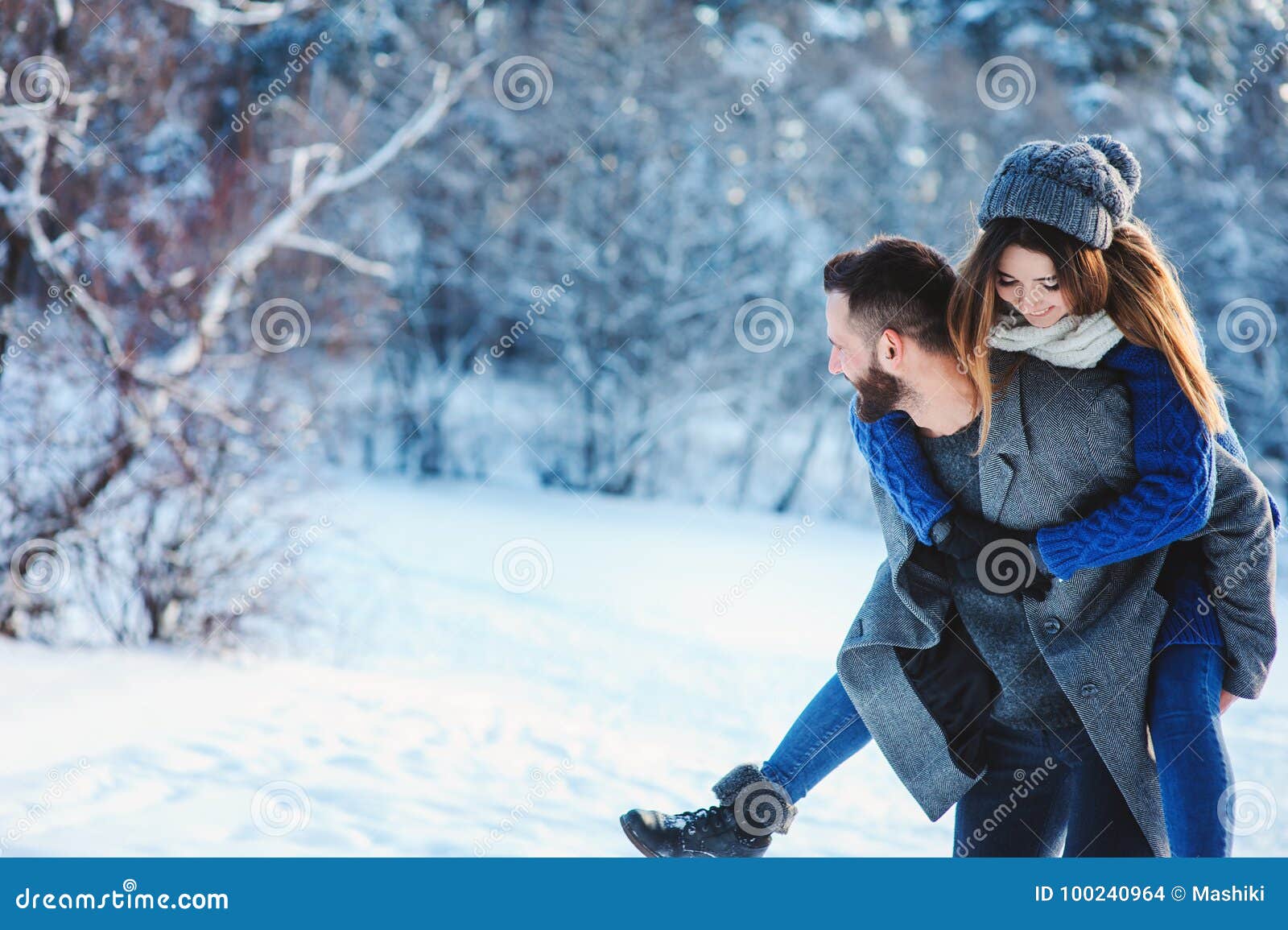 happy loving couple walking in snowy winter forest, spending christmas vacation together. outdoor seasonal activities