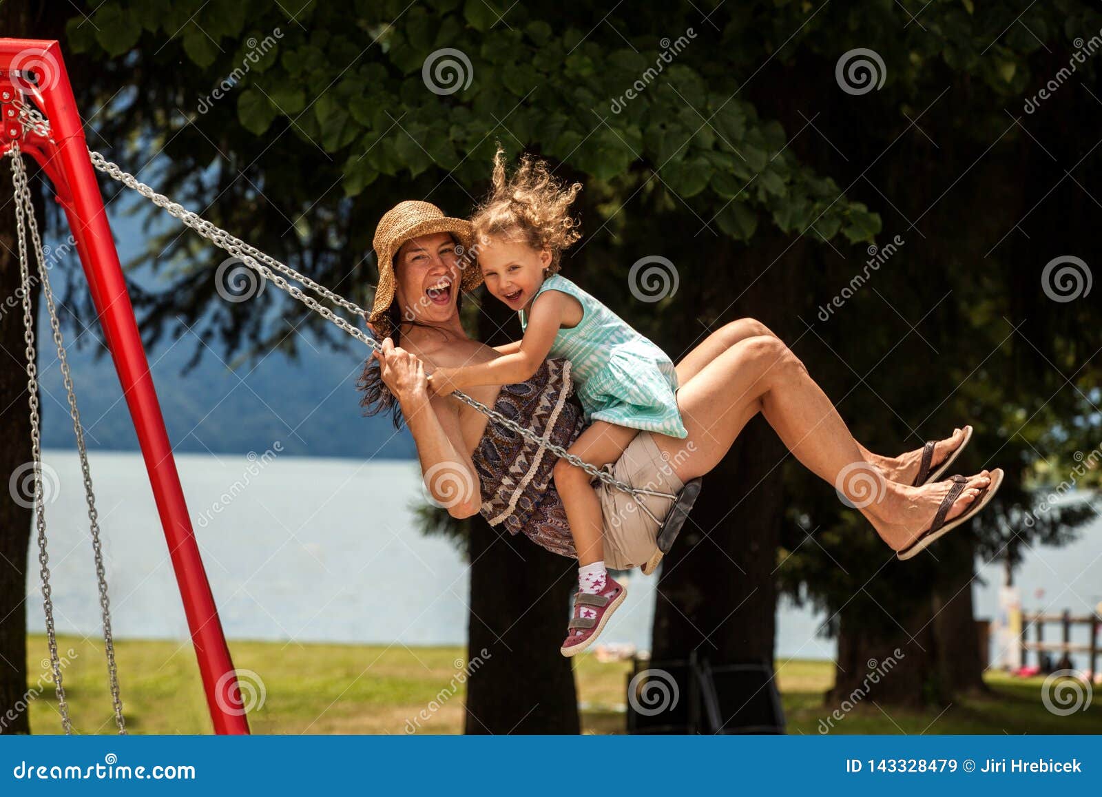 happy loving family! young mother and her child daughter swinging on the swings and laughing a summer evening outdoors, beautiful