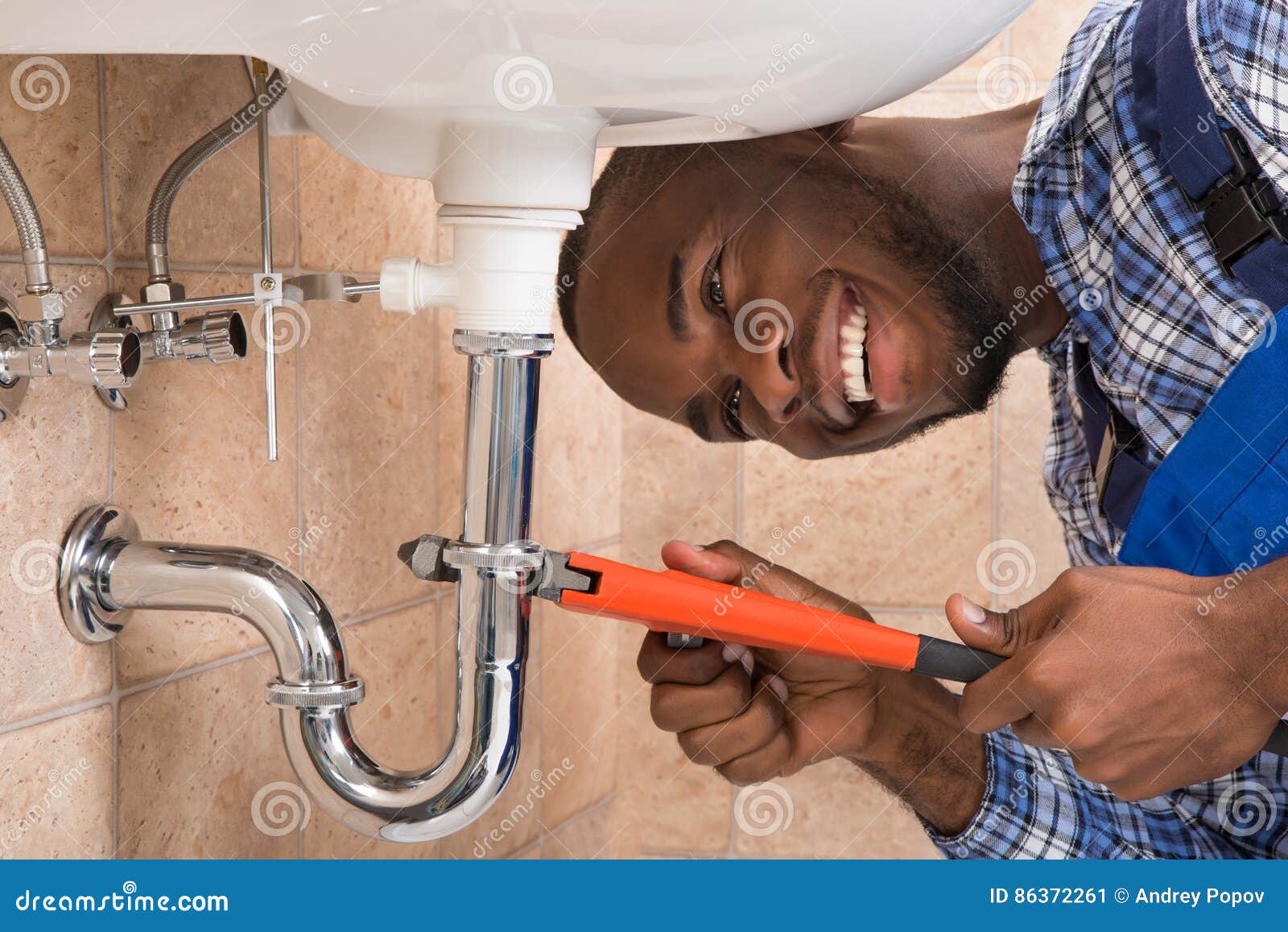 happy male plumber repairing sink in bathroom
