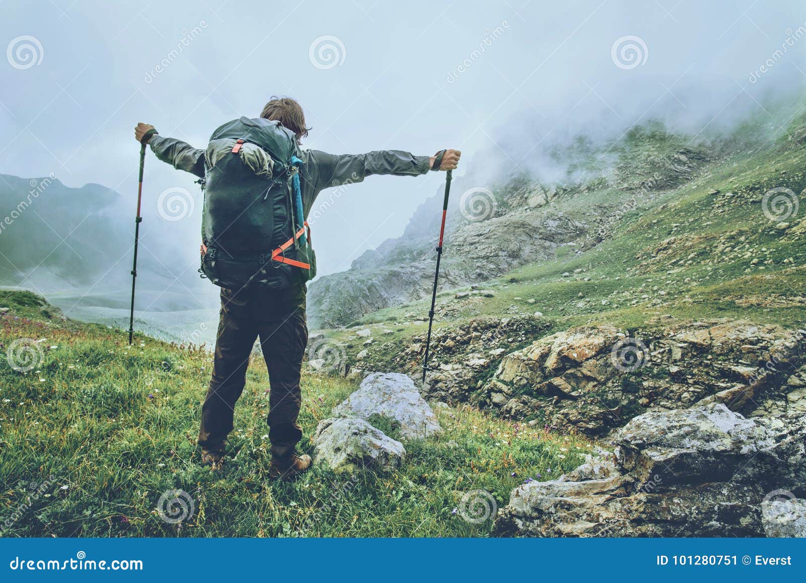 happy man backpacker hiking in foggy mountains