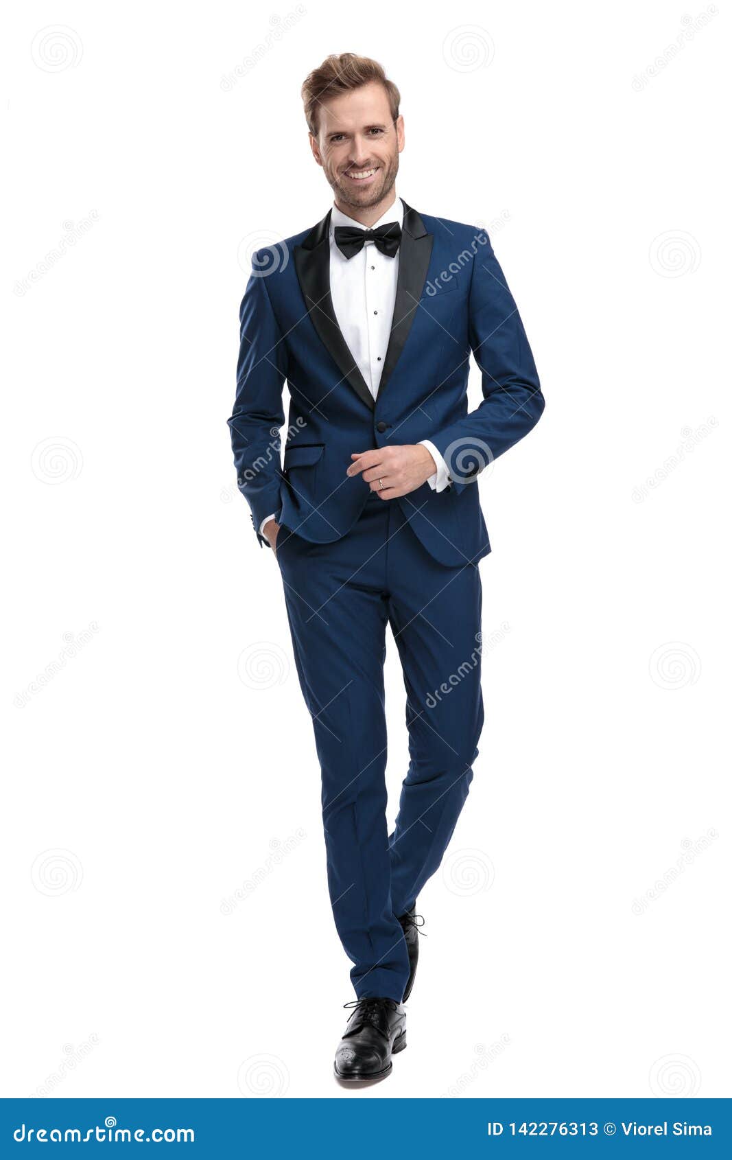 happy man in blue tuxedo walking with hand in pocket