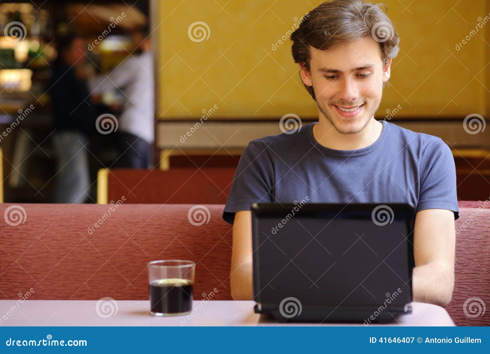 happy man browsing internet on a laptop in a restaurant