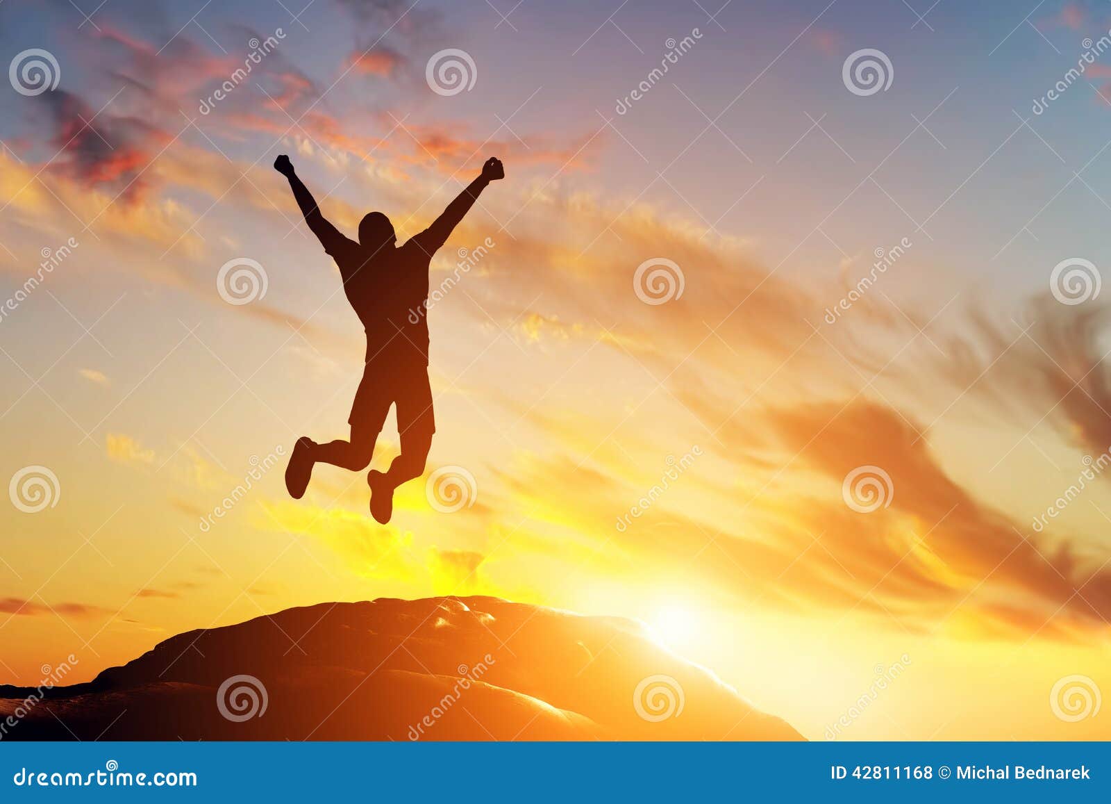 happy man jumping for joy on the peak of the mountain at sunset. success
