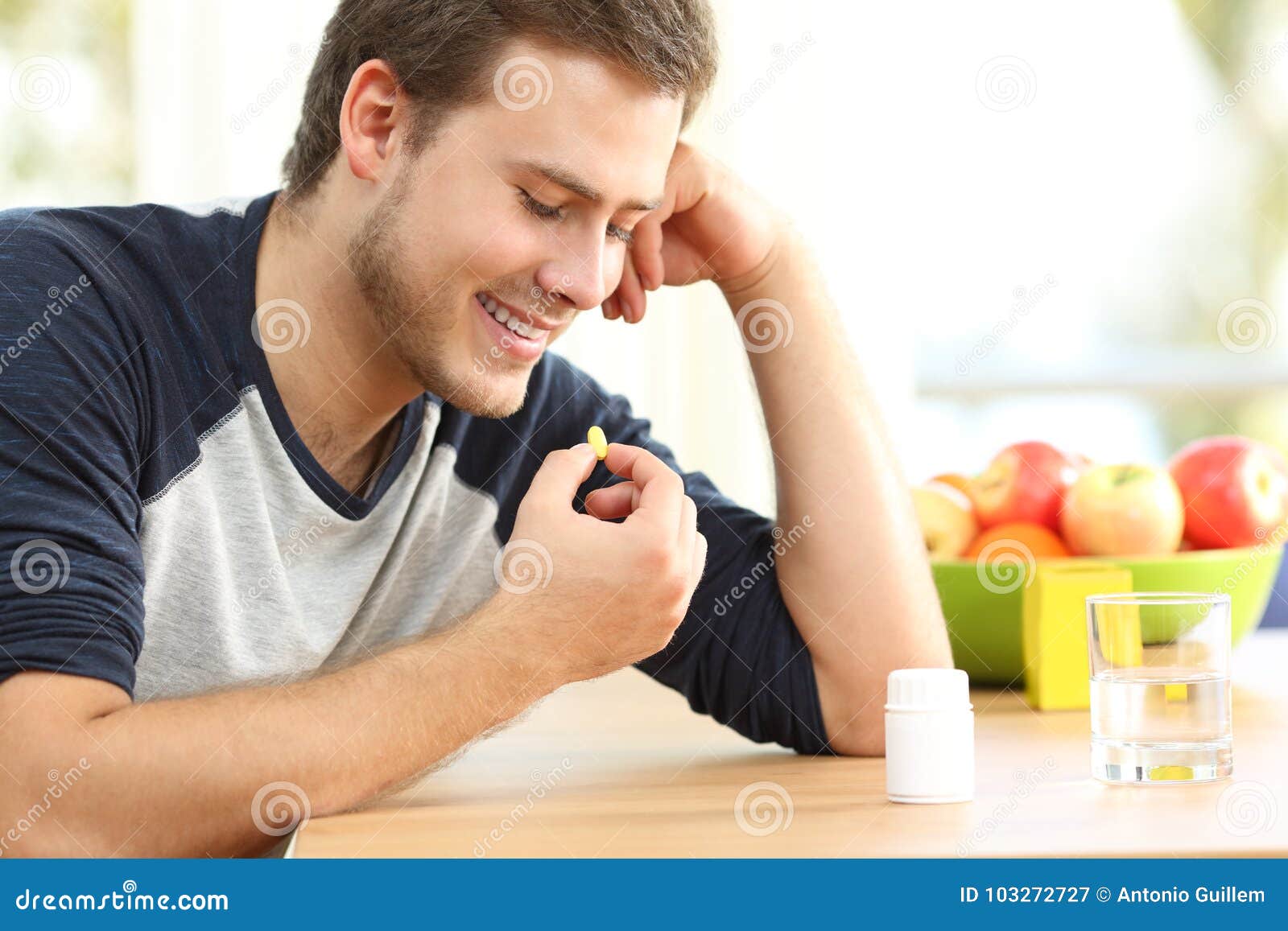 happy man taking a vitamin pill at home