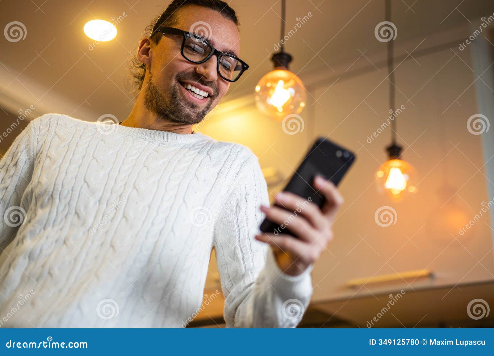 happy man using smartphone at home with warm lighting