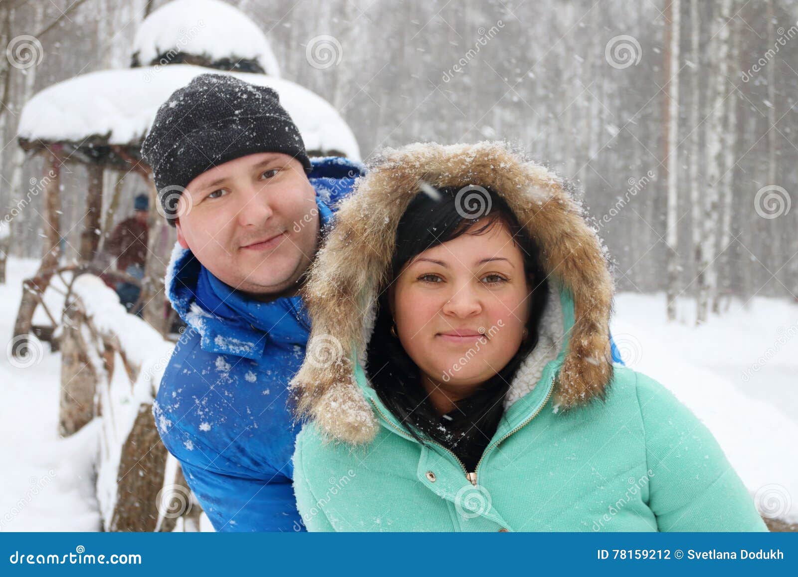 Couple posing in decorated winter studio with fir, christmas trees and snow.  Man holding hand on belly of wife. Beautiful pregnant woman wearing in bl  Stock Photo - Alamy