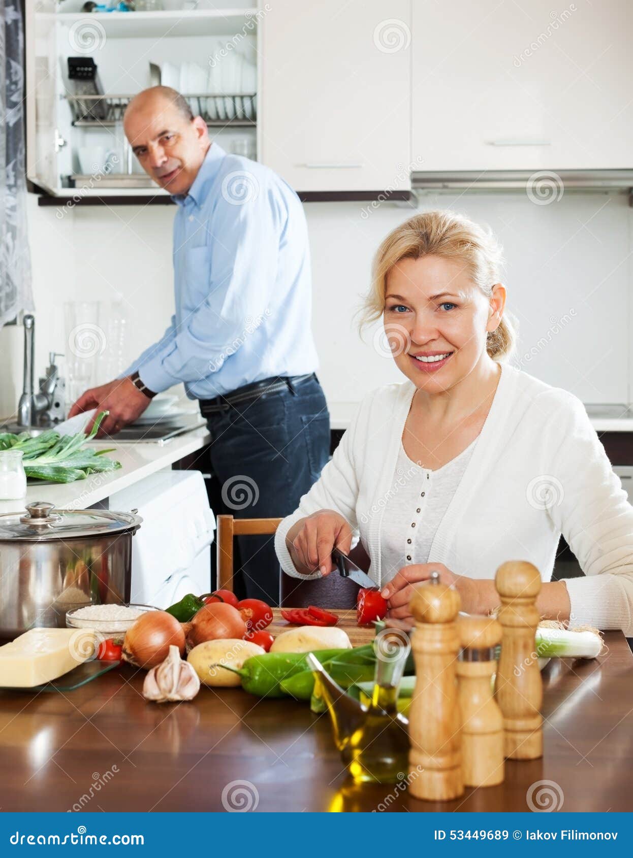 happy mature couple cooking spaniard tomatoes