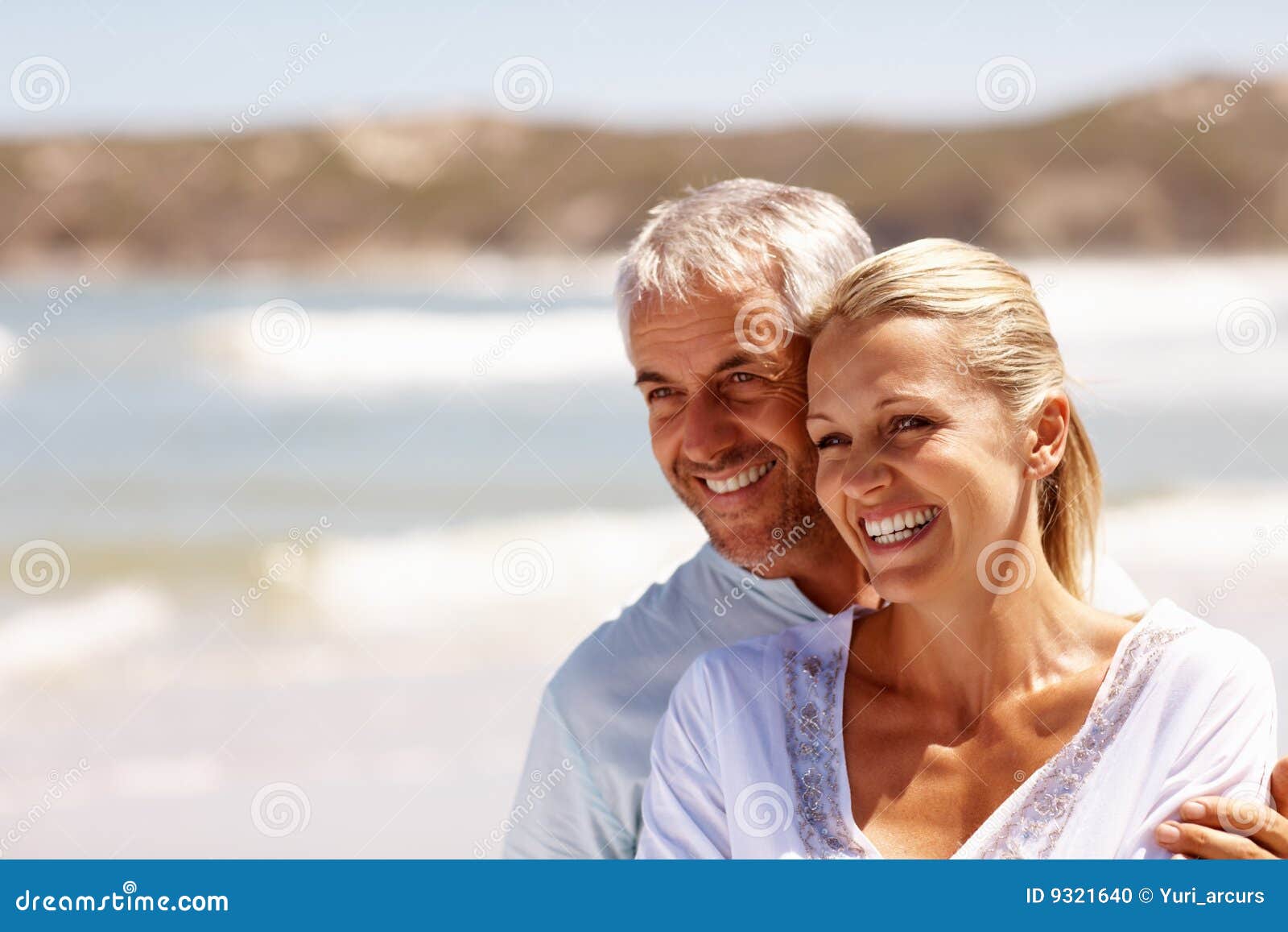 happy mature couple embracing at the beach