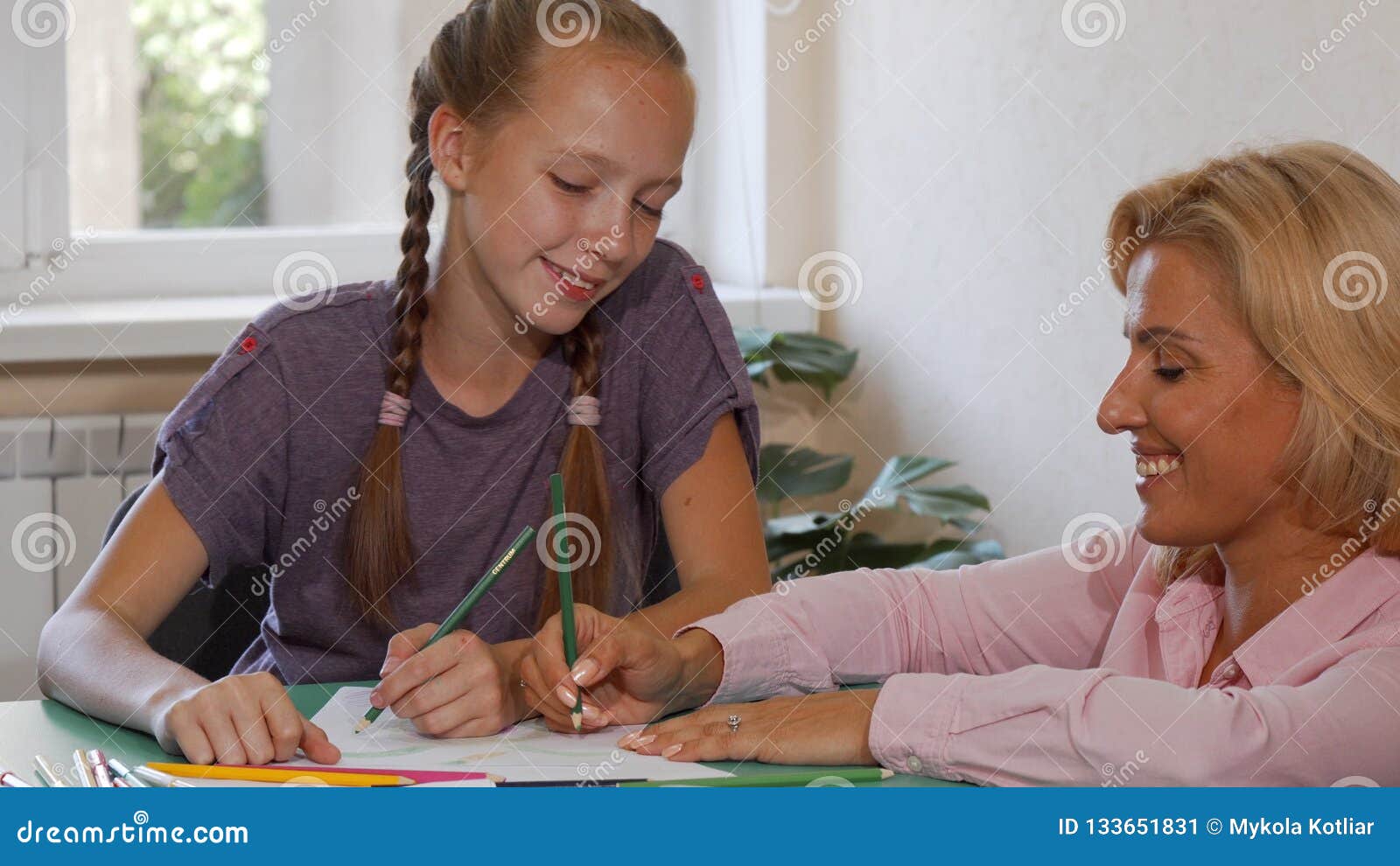 Happy Mature Female Teacher Drawing With Her Student At School Stock