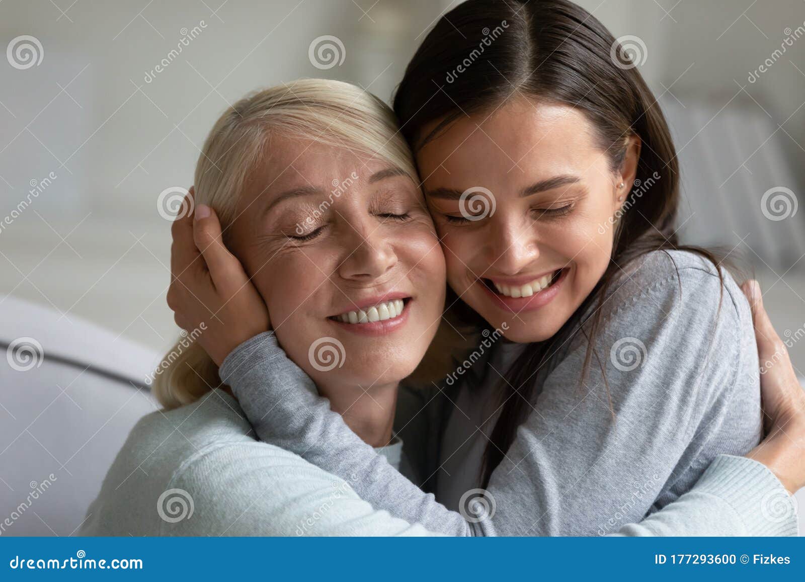 loving elderly mother and adult daughter hug at home