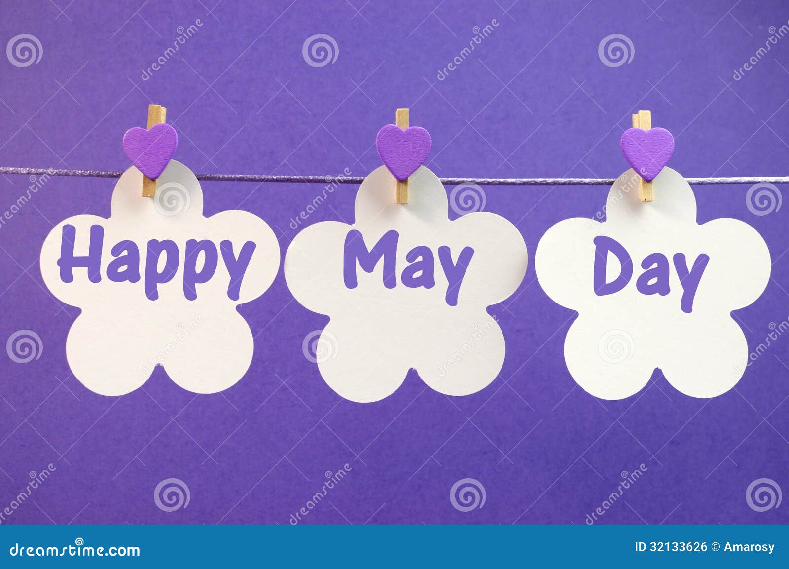 Happy May Day greeting message written across white flower cards with purple heart pegs hanging from pegs on a line for May Day, May 1, celebration.