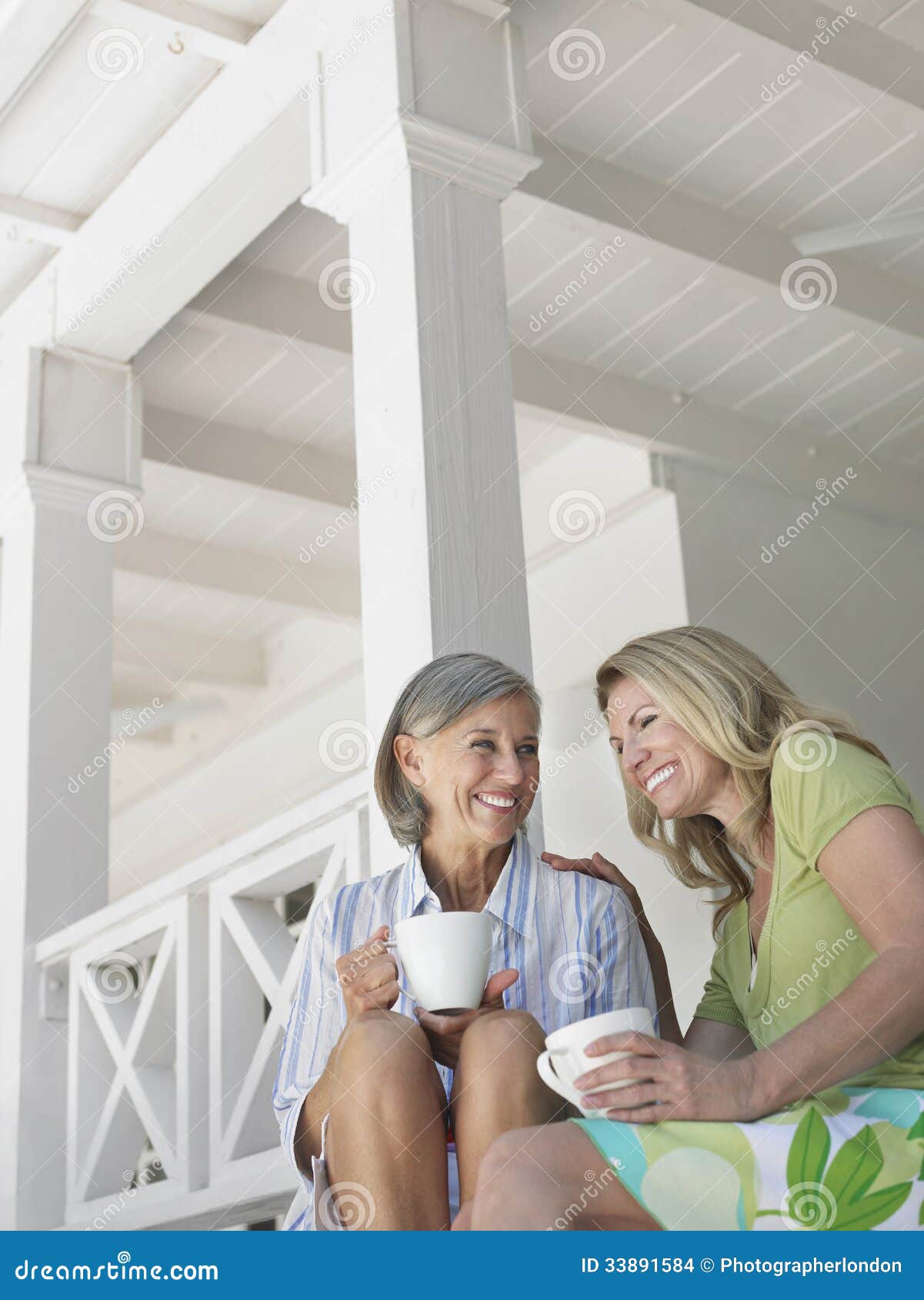 happy middle aged women on verandah with cups