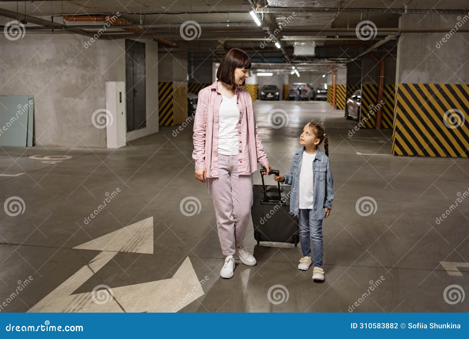 Happy Mom And Small Daughter Stroll Through Subterranean Parking Area Happy Mom And Small Daughter Stroll Through Subterranean Parking Area