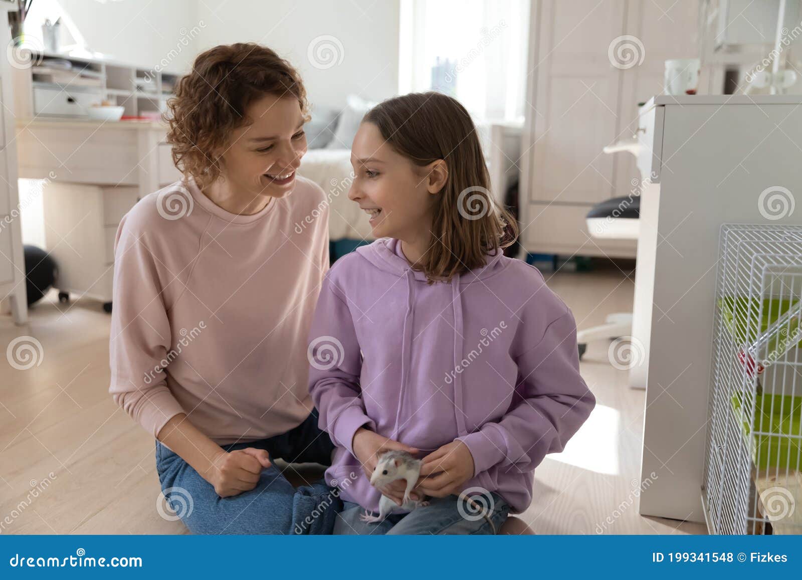 happy mom and teen daughter play with domesticated mouse