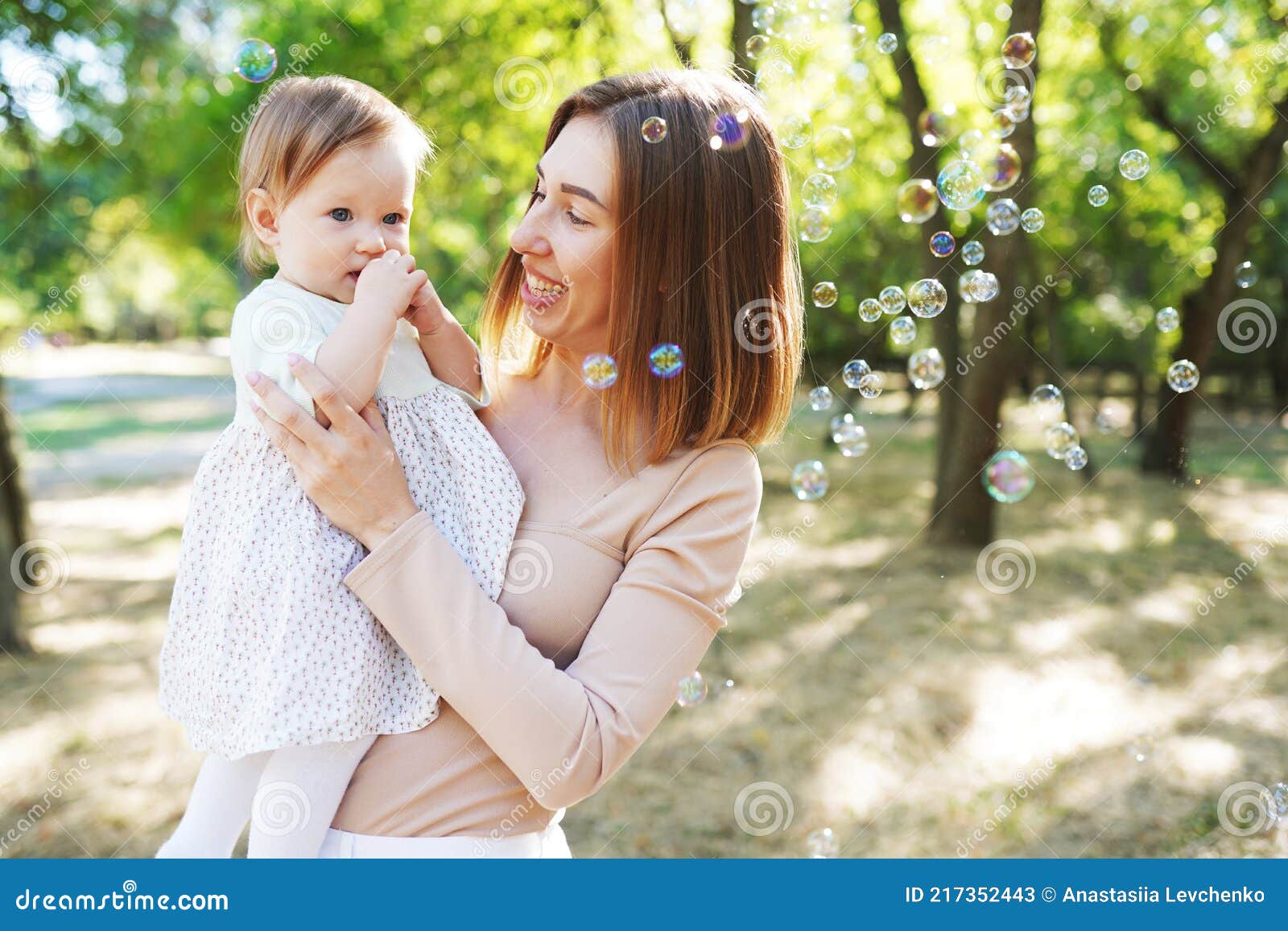 Happy Mother And Daughter Blowing Bubbles In The Park Stock Image