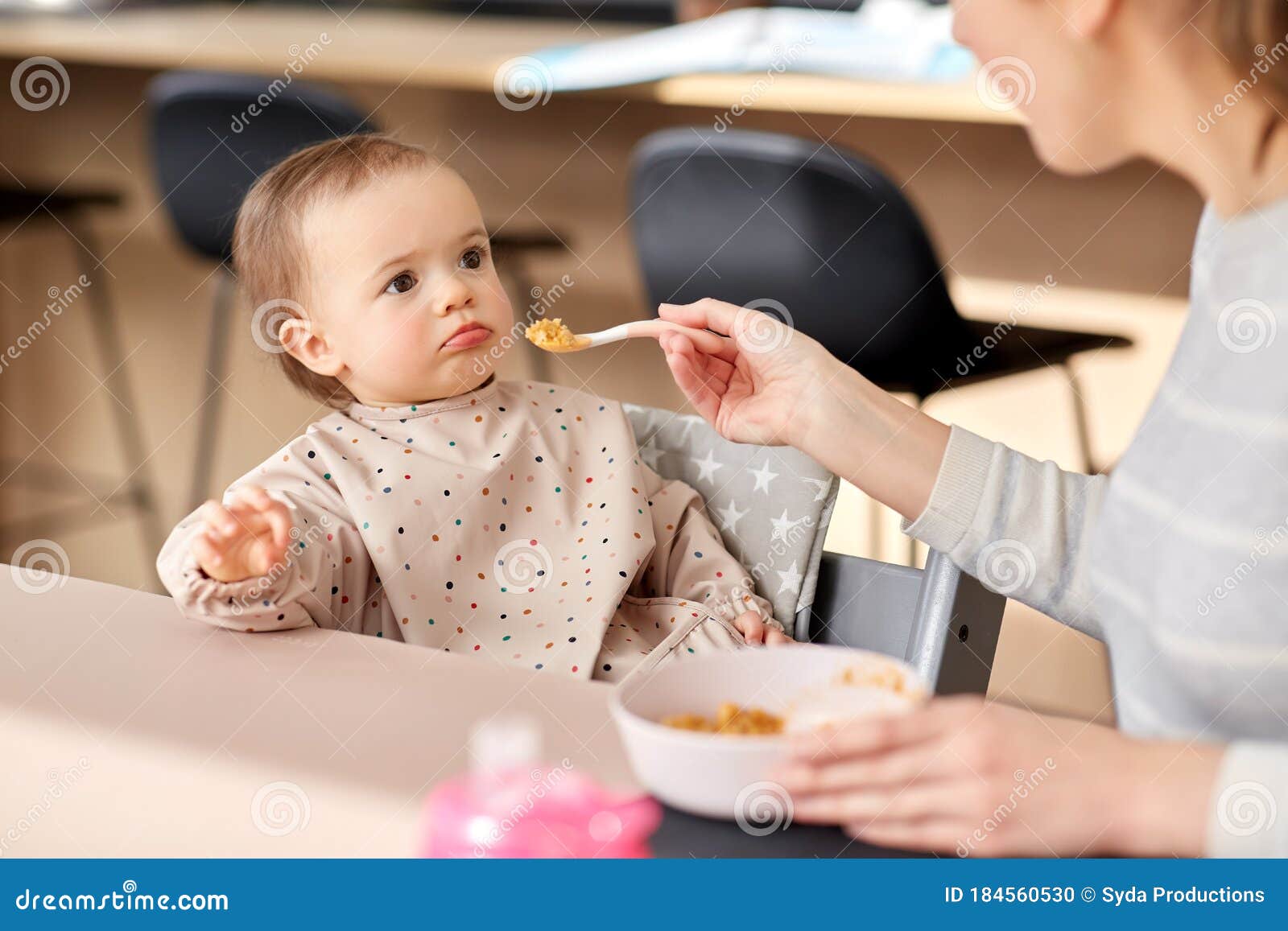 happy mother feeding baby with puree at home