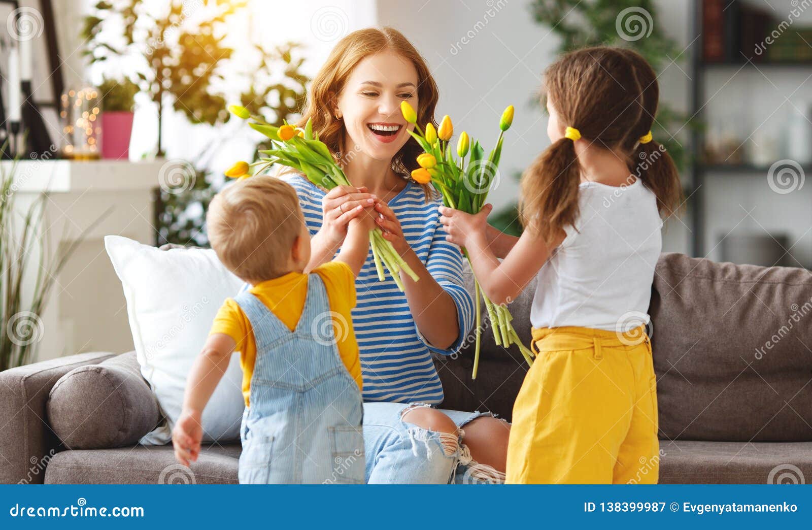 happy mother`s day! children congratulates moms and gives her a gift and flowers