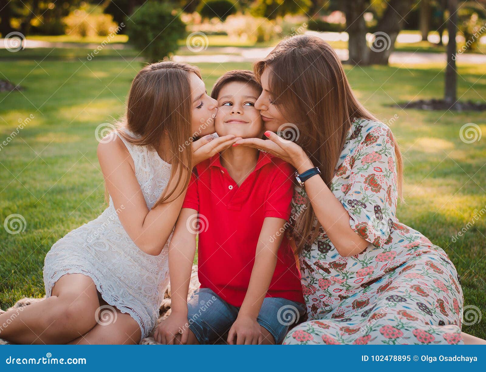Happy Mother, Son and Daughter in the Park. Mom and Sister Kiss Their