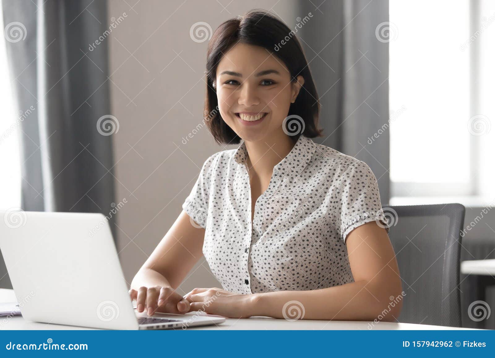 happy motivated asian female employee working with computer portrait.