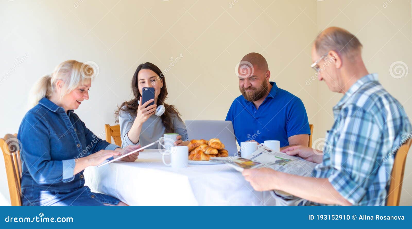 happy multi generational family reading news in the morning while having breakfast