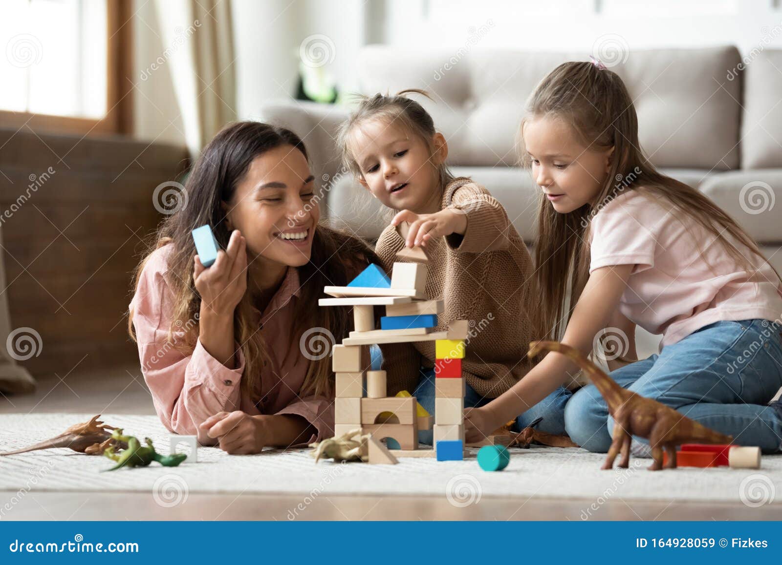 happy mum with kids daughters playing toys on floor