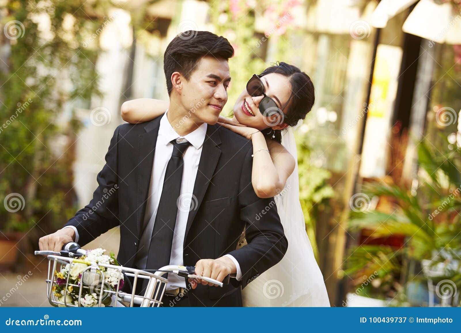 asian newly wed couple riding a bicycle