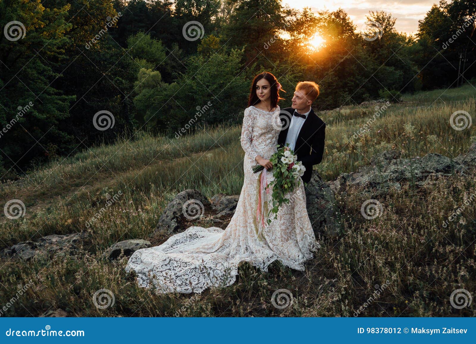 happy newlyweds are sitting on a rock in the nature