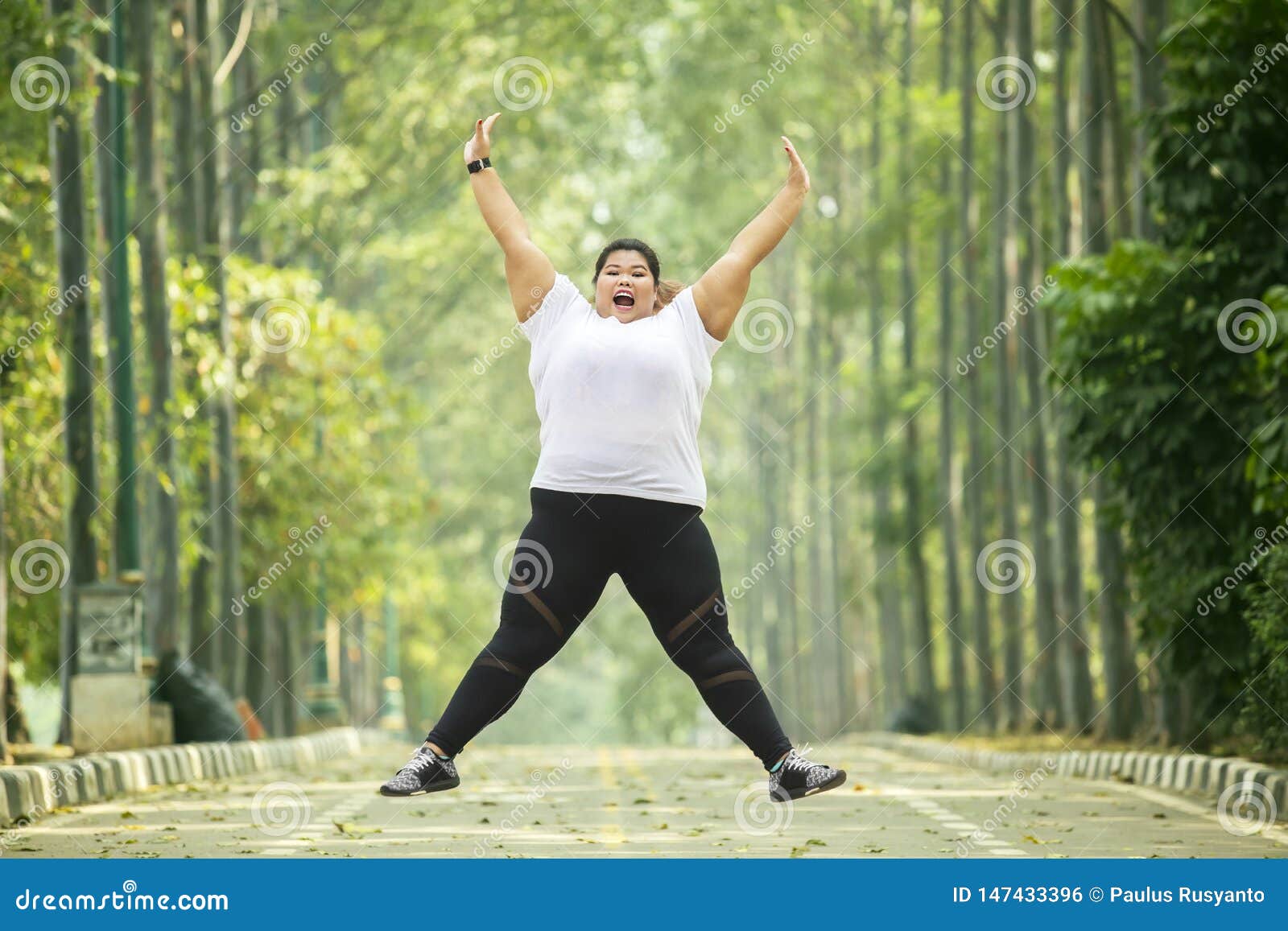 happy obese woman jumps on the road